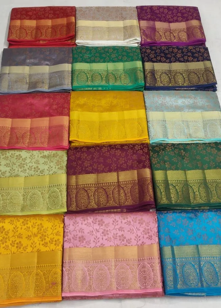 Collection of colorful traditional silk sarees with golden zari borders neatly folded and displayed